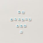 Minimalist composition of Scrabble tiles spelling 'Me, Myself, and I' on a white background.
